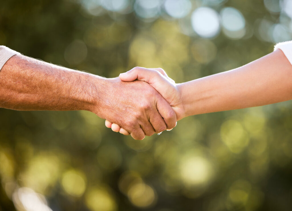 Two people shaking hands over a business deal